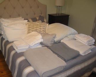 Queen bed with tufted headboard, lots of linens