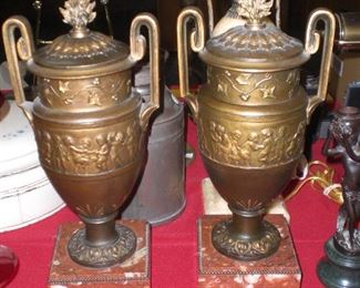 pair of 17" French spelter patinated lidded urns with flame form finials and dancing cherubs on red and whith marble bases 