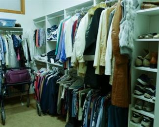 Walk-in closet loaded with professional woman's clothing and a few men's items.