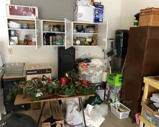 Garage filled with small appliances, small weber grill, Christmas decorations, dishes, cabinets filled