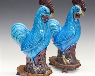A Pair of Chinese Porcelain Roosters. Each is aqua blue with purplish-brown accents and are on conforming wood stands. Wear to the glaze at bases, minute flake to one's comb. 11 1/4" high overall.