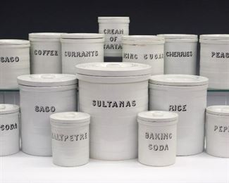 A Set of Fourteen Maling Pottery/Cetem Ware Kitchen Canisters, c. 1900. White cylindrical covered canisters with black lettering including sultanas, sago, rice, icing sugar, peas, currants, cherries, coffee, pepper, cream of tartar, baking soda, and saltpetre. The majority with various stamped Cetem Ware markings. Crazing and some flakes/damage. Up to 8" high.
