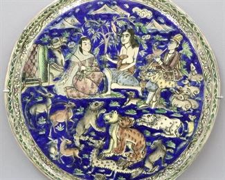 A Persian Glazed Ceramic Tile, Late Qajar Dynasty. Round form with imagery of three figures in the midst of numerous wild animals, decorated in polychrome glaze of azure, green, brown, white, yellow, and puce. Qajar Dynasty, 1789-1925. Several glued repairs, crazing evident, areas of repair about the rim. 19 3/4" diameter.