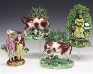 Four 19th century Staffordshire figures. Depicting a woman reading, a couple holding baskets and a pair of cattle. All with bocages, molded bodies with polychrome decoration. All with minor damage and/or repairs to bocages, the woman (couple) has loss to the hat, the bull lacks a horn, the cow has a damaged horn and repaired tail, the reader has glued repairs to the upper bocage, some crazing. Up to 7 3/4" high.
