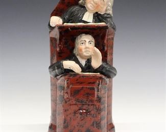 A 19th century Staffordshire figure entitled "The Vicar and Moses". Molded figure with two black robed figures in a brown pulpit with black brushed decoration. Minor wear, slight loss to the decoration. 9 1/4" high.