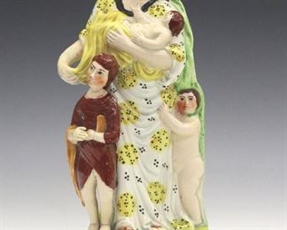 An early 19th century Staffordshire figure of "Charity". Molded figure of Charity holding a baby with two young children standing at her feet, having polychrome decoration. Some surface wear, the young boy with a tiny flake at his fingers. 9 1/4" high.
