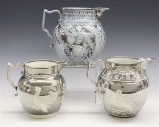 Three 19th century English Pearlware jugs with Silver lustre decoration, one on a pale Blue ground. All with flowers and foliage the two White ground jugs with Parrots. Wear, crazing, light surface scratches, minor spout flakes, the Blue jug with two shallow flakes inside foot rim. Up to 6 1/4" high.