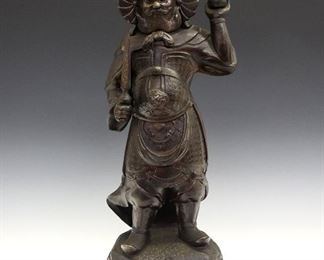 A Japanese Ceramic Figure of a Deity. Dark brown stoneware figure of Bishamon (Bishamonten) the god of fortune in wars and battles, one of the Seven Lucky Gods of Japan, is shown holding a spear in his right hand and a pagoda in his left. Very minor wear overall. 18 1/2" high.