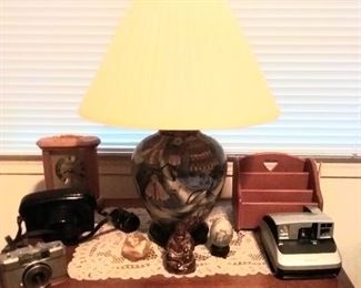 Top of end table with display  of vintage cameras,  misc Orientalia, battery powered carriage clock, lamp with oriental  ceramic base.