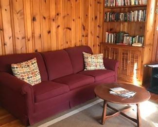 Nice sofa, decorative pillows, round coffee table, room rug, books, more
