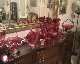 Cranberry glass galore! Large gold buffet mirror.  GWTW and Fenton glass floor lamps throughout home. This beautiful buffet with glass on  top goes with the dining room suite. 