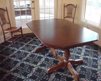 Kitchen Area:  A beautiful double pedestal wooden table measures 68" x 44" and comes with one 18" leaf.  It rests on a large octagonal black/vine trellis pattern rug that measures 9'  1"  x  10'  10."  A smaller identical rug is nearby.  