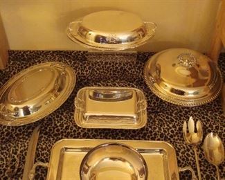 Dining Room:  Four silver-plate casseroles are shown with a silver-plate tray and bowl, as well as a carving set, and a large fork/spoon set.