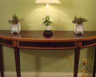Hall on the way to Master Bedroom:  This beautiful  Hepplewhite-style demi-lune console table in mahogany and satinwood has bellflower and fan inlaid designs (see next photo). It is by COUNCILL and measures 54" wide x 15-l/2" deep x 32" tall.  The floral lamp is porcelain, and the two small blue/white planters are by CHELSEA HOUSE (they match the larger ones on the family room mantel).  