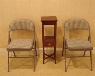 Lower Level: Shown are two of a set of four quality grey/upholstered folding chairs.  The small table in the middle is for sale.