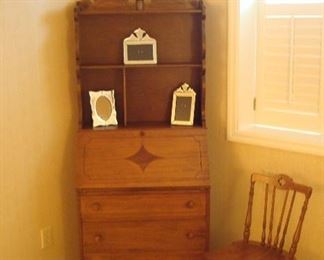 Lower Level-Bedroom: A cute petite secretary has divided upper shelves, a slant front dropleaf, and three lower drawers.  The chair is separately priced, as are the mirrored photo frames and waste can.