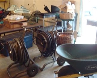 Garage:  Hoses on wheeled stands, shelving units, and a wheel barrel are for sale.