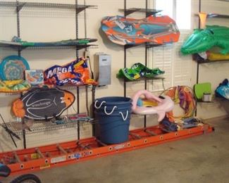 Garage:  Pool rafts and boogie boards are shown with large plastic barrels.  Also shown is a WERNER 28 foot extension ladder (D6228-2) with 300 pound capacity.