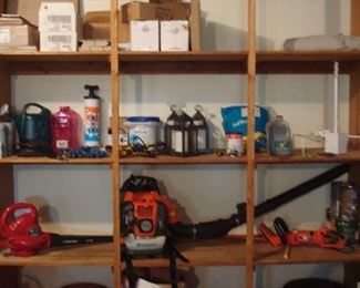 Garage:  Some chemicals and small lanterns are shown above:  a TROY-BUILT Blower; a HUSQVARNA 150BT gas powered backpack/hand-held blower; and a BLACK & DECKER Hedge Hog trimmer.  The lower shelf display various terracotta and resin planters.