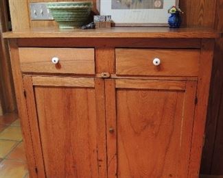 Antique oak jelly cupboard with original porcelain knobs on two drawers, paneled doors.