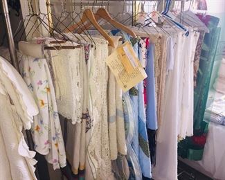 racks of vintage table cloths, bedspreads, Christmas linens, hand crocheted spreads, and two Amish quilts