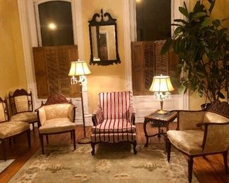 Golden high-armed chairs with matching side chairs, marble side table, sturdy red striped chair, crystal-trimmed lamps