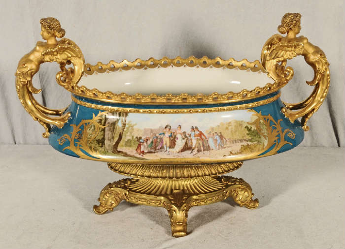19th C.  FRENCH PORCELAIN CENTER BOWL.  BRONZE BASE.  GILT PORCELAIN FIGURAL HANDLES.  FIGURAL PANEL ON THE FRONT SIGNED  A. CARRIER.  P. C.  LANDSCAPE PANEL ON THE BACK. 16"  H   X  24"  W.