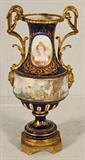 ANTIQUE COBALT SEVRES PORCELAIN URN. PORTRAIT OF A LADY. PAINTED FRIEZE DEPICTING CUPIDS AROUND THE MIDDLE. BRONZE SCROLLED HANDLES AND BASE. GILT FLORAL DECORATION. SOME GILT & BEJEWELING IS OFF. 23 1/2" H X 10" W X 8 1/2" D.