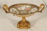 ANTIQUE BRONZE ROSE MEDALLION CANTON COMPOTE. FRENCH BRONZE BASE, HANDLES AND MOUNTS. GOOD. 7 7/8" H X 13 5/8" W X 10 3/8" D.
