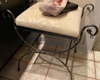 a bench of iron with a fabric seat in the bath area