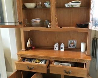 BUFFET.  Oak buffet in excellent condition with lighted shelf.  Includes two glass shelves in top two window cupboards, two drawers and three lower cupboards. There is a plate groove around the inside of the top half for display.  
(W 49”, H 78”, D 56”) $140