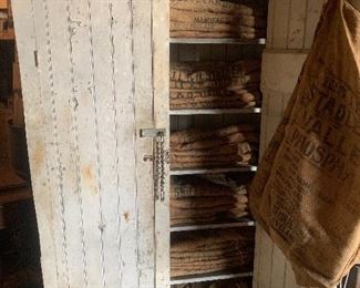 Primitive farmhouse winter white cupboard with interior shelves, a plethora of vintage Feed Sacks