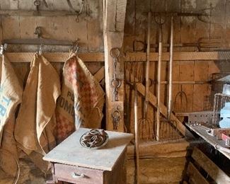 Assortment of antique and primitive pitch forks, feed sacks, antique wood work table/cabinet, old wood gates, single tree horse accessories 