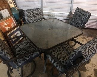 Glass patio table with four rocking and swivel chairs