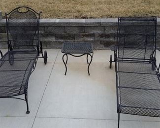 Two wrought iron chaise patio loungers with side table