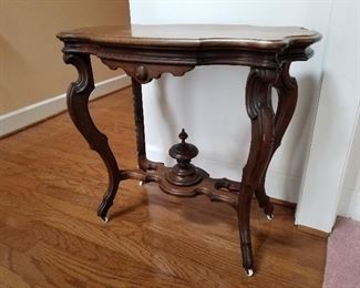 Lot # 5 - $175  Victorian Table with casters (Table is light weight).  Caster are very small and white.  2 ft. 8" wide, 2 ft. 5" height & 1 ft. 8" across table top from top/bottom. 