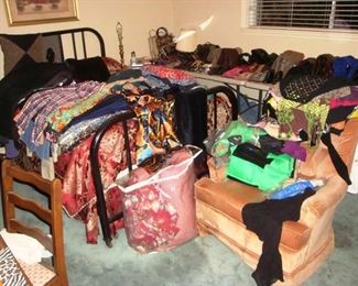 Bedroom full of boots, purses & ladies clothing with queen bed