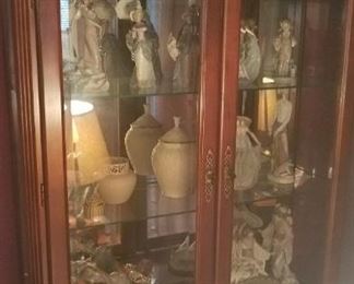 Curio full of LLadro and more porcelain collectibles.
