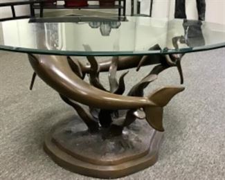 Cast bronze dolphin cocktail table with oval beveled glass top. 45” x 32” x 20”
