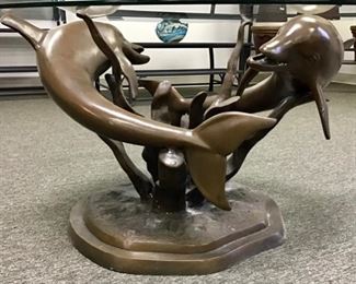 Cast bronze dolphin cocktail table with oval beveled glass top. 45” x 32” x 20”