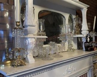 Lot 814 White Mirrored Fireplace Surround, White Shelves- Wooden white mirrored fireplace surround approx 7ft tall and 5ft wide; 8 candle holders; white dish; 4 pieces of clear glassware; two white wooden book shelves; sculpture; wall lamp with two lights; floral fireplace 