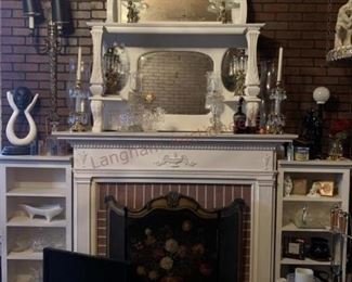 Lot 814 White Mirrored Fireplace Surround, White Shelves- Wooden white mirrored fireplace surround approx 7ft tall and 5ft wide; 8 candle holders; white dish; 4 pieces of clear glassware; two white wooden book shelves; sculpture; wall lamp with two lights; floral fireplace 