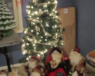 Seven foot pre-lit Christmas tree with a few of the Santa Claus figurines available at this sale.