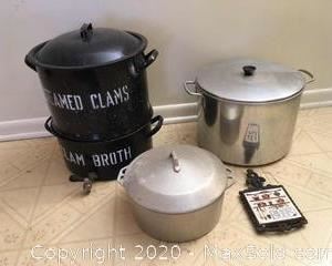 Black enamelware clam steamer with clam broth spout compartment. Large aluminum stockpot with circular wire rack.