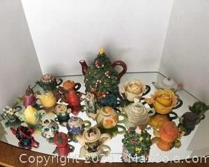 A large assortment of decorative mini teapots and one large Christmas tree teapot with matching salt and pepper shaker