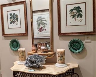 Vintage LaBarge wall mirror, pair of nicely framed/matted botanicals, iron/travertine table and collection of majolica pottery plates. 