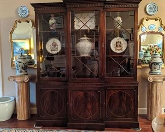Vintage English flame mahogany breakfront, flanked by carved pine pedestals, topped with vintage Asian ginger jars, pair of vintage LaBarge gold gilt wall mirrors and pair of Asian blue/white porcelain plates. 