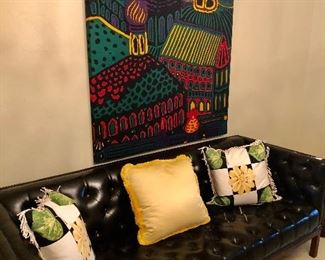 Tufted leather sofa with large textile art wall hanging