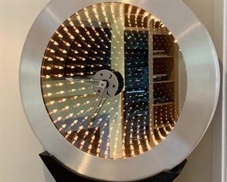 "Endless Time" Grandfather clock takes light and space to a new level of visual excitement! When you peer into this dramatic clock, you will see the optical illusion of thousands of LED light reflections appearing to descend back more than 10 feet from the clock face to the rear in perfect order!