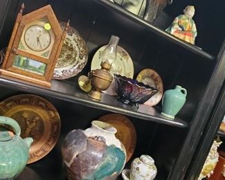 Top shelf, L to R: Red Wing grey vase with maroon interior, discounted price now $10; Shea black pottery vase (as is), discounted price now $22.50; seated Asian man with base, discounted price now $17.50
2nd shelf, L to R: Antique Telechron handpainted electric clock (as is), discounted price now $20; German rectangular brown transferware serving platter, discounted price now $97.50; brass kerosene sconce lamp, discounted price now $25; carnival glass footed fruit bowl, discounted price now $17.50; turquoise pottery jug, discounted price now $10
3rd shelf, L to R: Large turquoise pottery teapot (as is), discounted price now $32.50; large artisan ginger jar pot, discounted price now $45; gold Imari lidded ginger jar, discounted price now $10; gold Imari bowl, discounted price now $7.50; carved wooden charger plates, discounted price now $9 each
Bottom shelf, L to R: Asian planter with peaches, discounted price now $45; large artisan Raku ginger jar pot, discounted price now $22.50; As